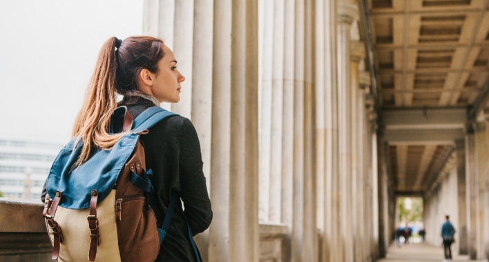 A young girl traveler or tourist or student with a backpack travels