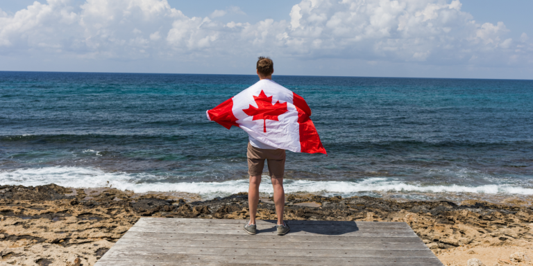 Man Holding Canada's Flag at the Beach