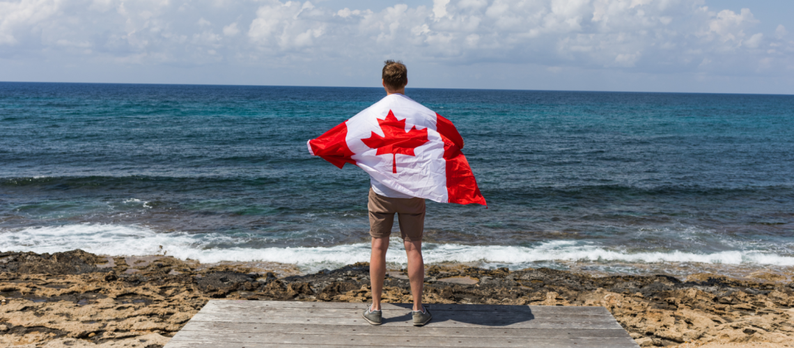 Man Holding Canada's Flag at the Beach